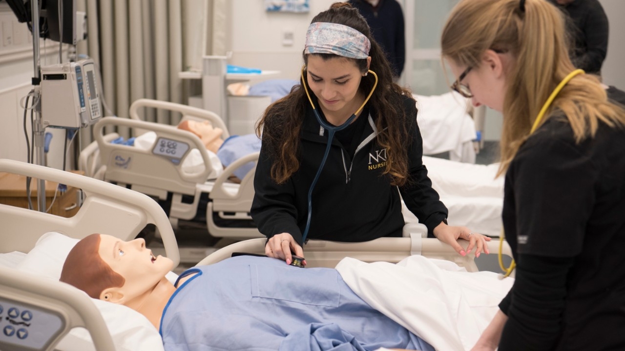 Two nursing students working in simulation lab