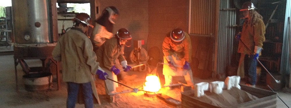 Students conducting bronze pour with flames