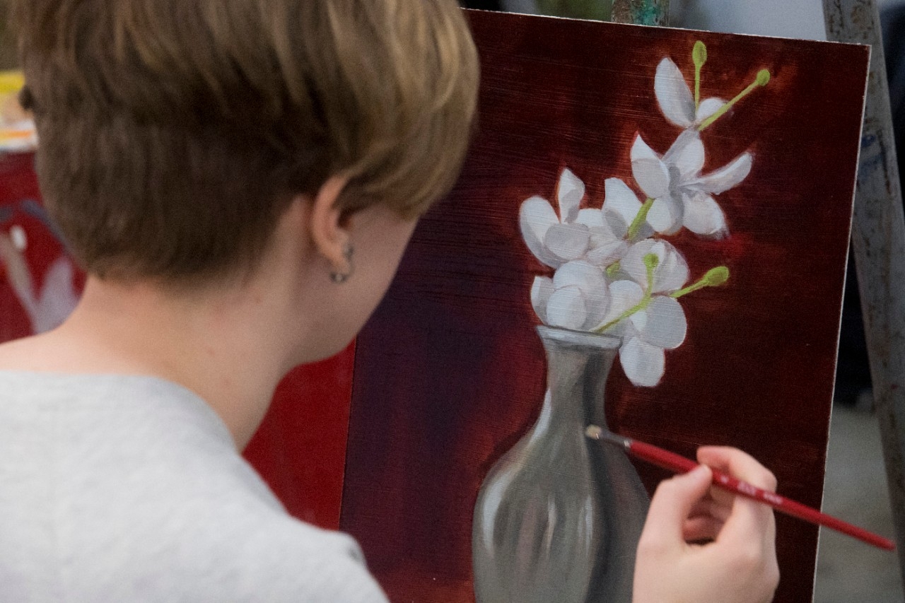 student painting a vase of flowers