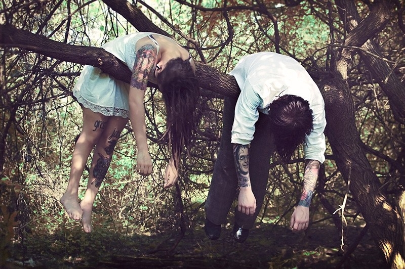 People draped over a tree limb in a forest