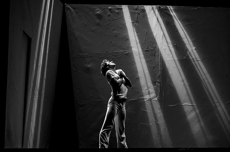 Jenfer DunhamCarmen black and white photograph of a person standing looking up while light shines down through a window