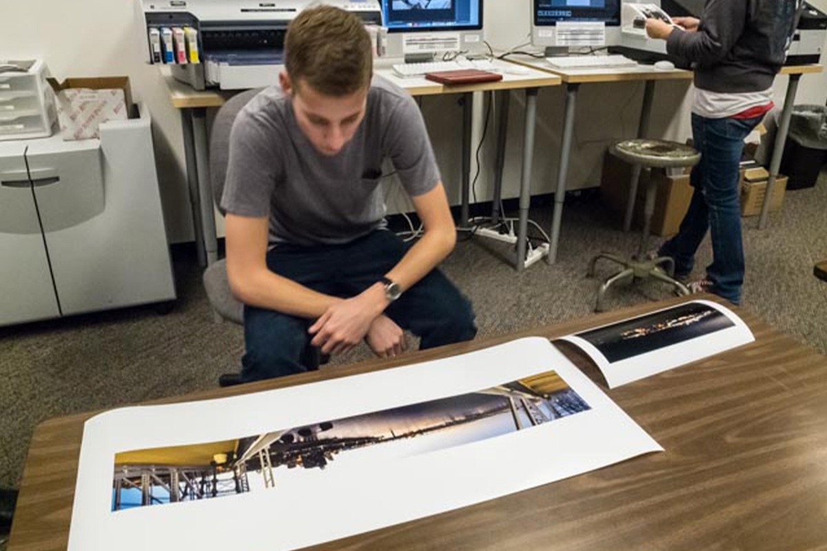 Young man looking at photos printed at the SOTA 4th floor print Lab