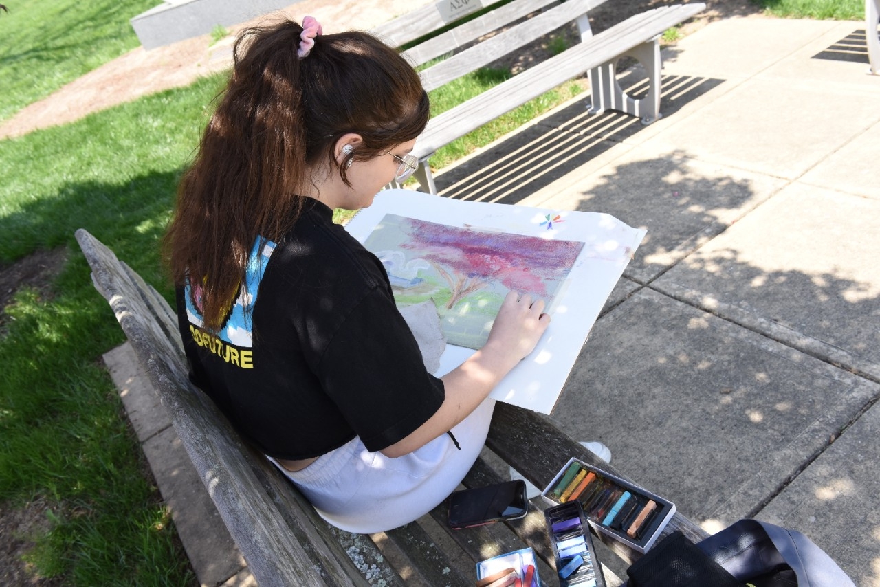 Student sitting outside working on a drawing