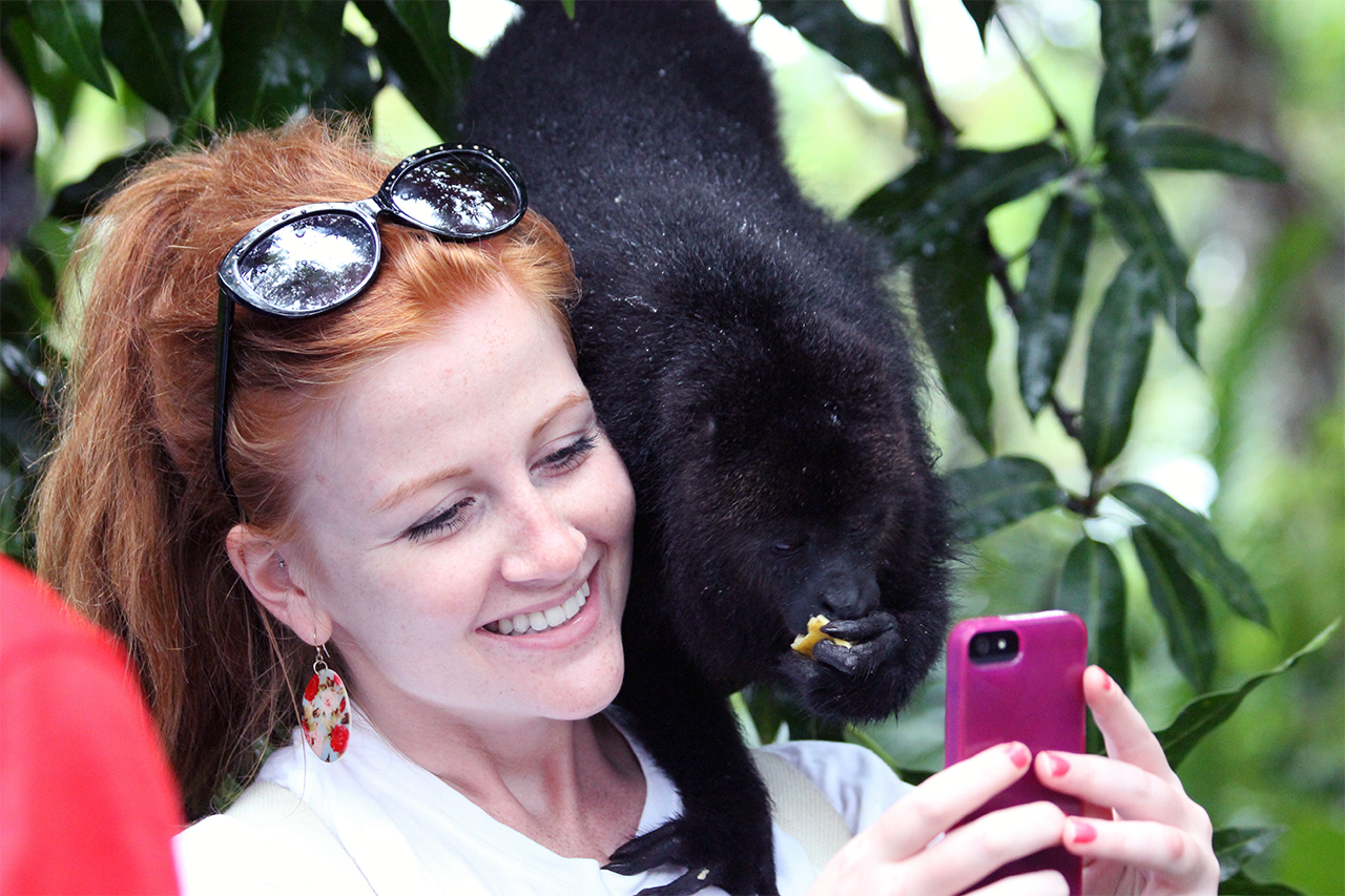 Woman taking a selfie with a baboon on her shoulder. 