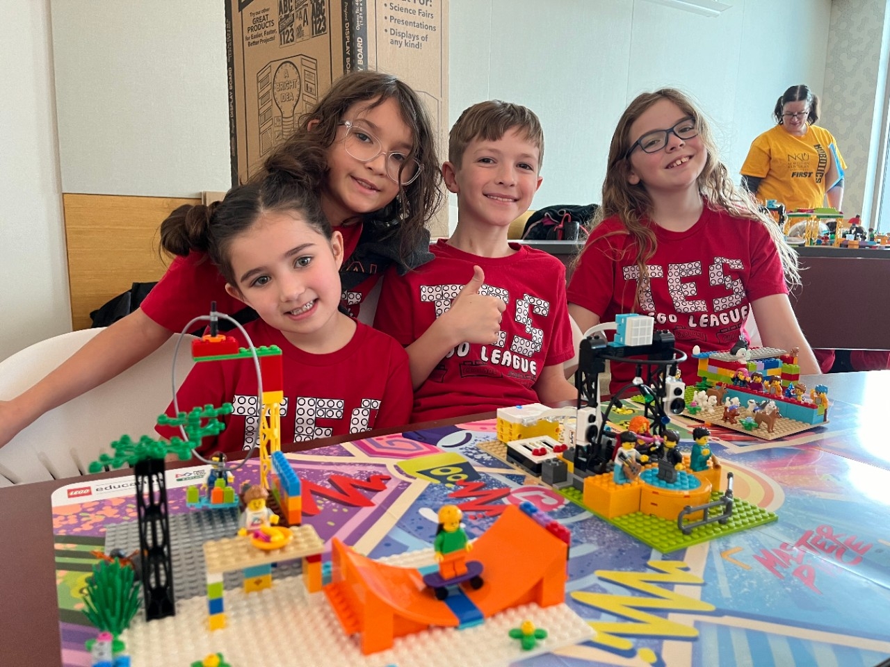 Elementary-aged students smile for the camera with their team's colorful LEGO robotics creations at the annual FIRST LEGO League Explore Festival at Northern Kentucky University.