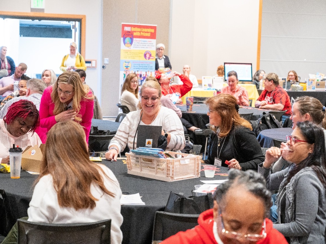 Conference attendees smile and mingle while looking at raffle prizes.