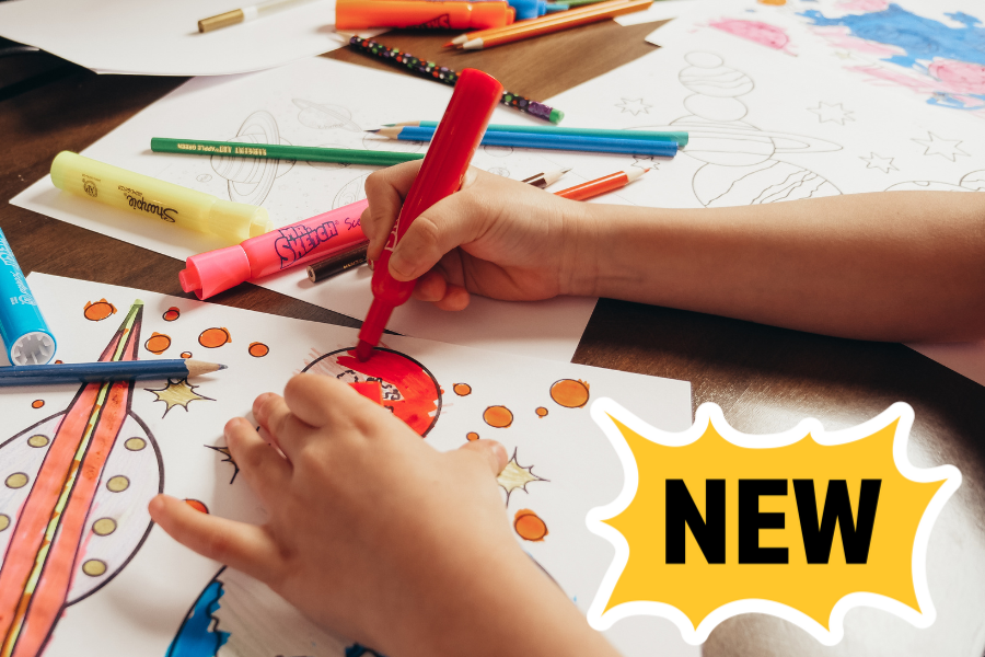 A child's hands colors pictures of planets with markers. The image includes a callout that says, "NEW," to indicating that it's a new camp.