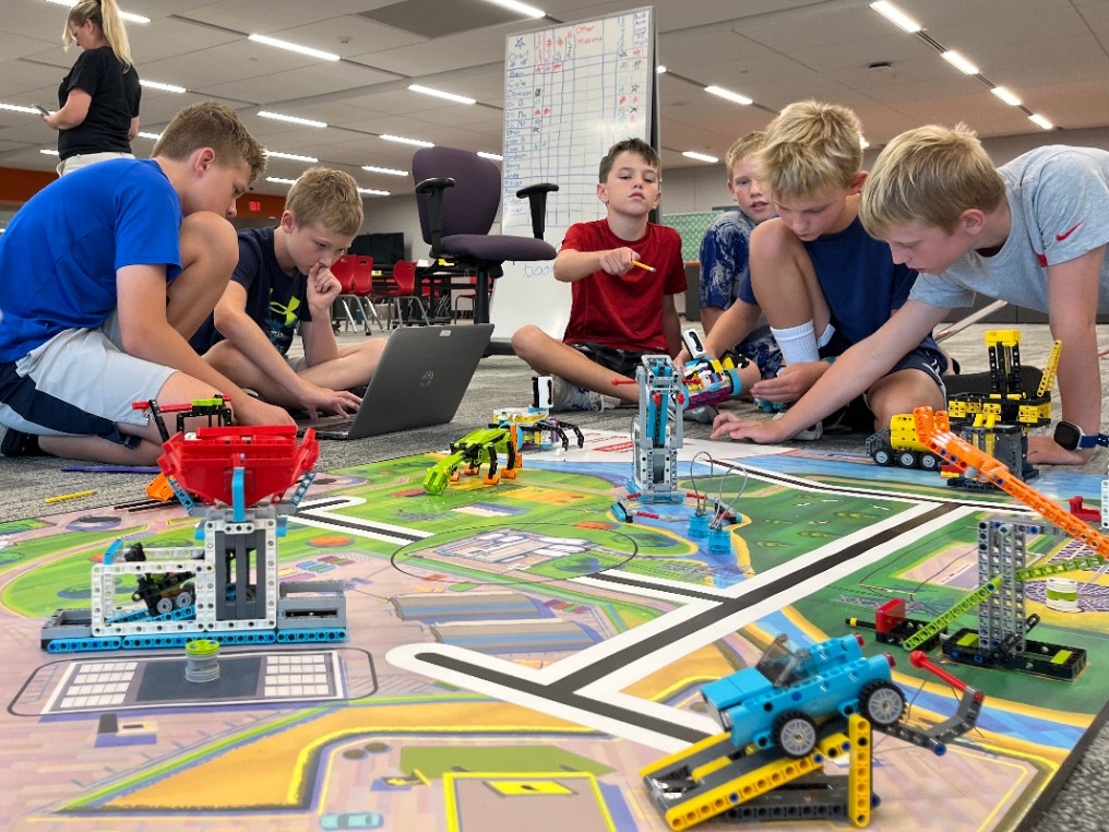 Young kids using elementary programming software to build and code a moving LEGO robot