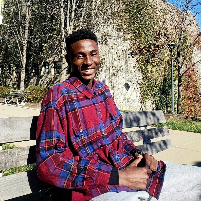 Joshua Osakwe sitting on a bench outside