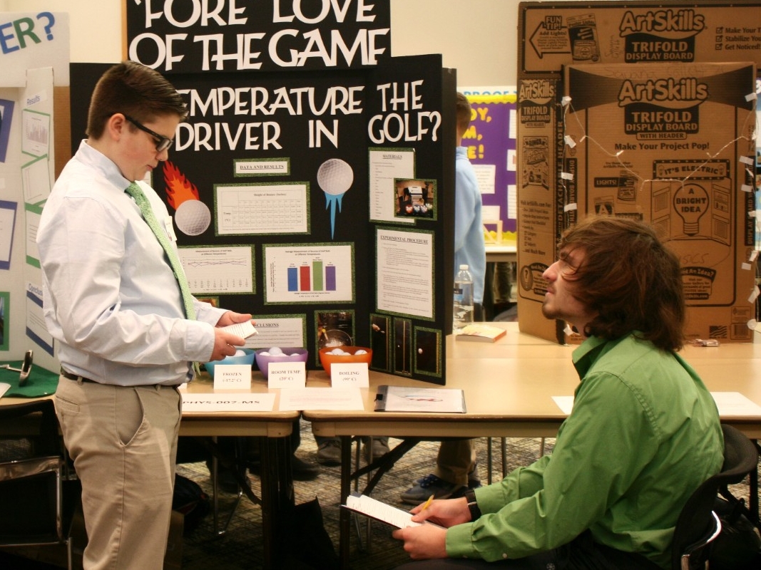 Elementary-aged child presents their poster to a judge at the Science and Engineering Fair of Northern Kentucky
