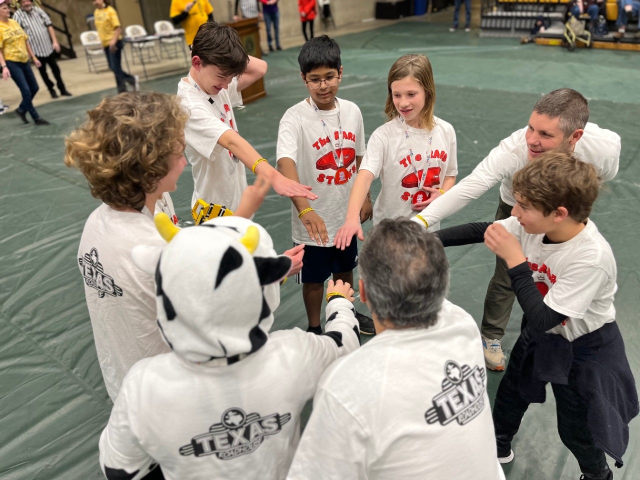 An award-winning teams puts their hands in for a victory cheer at the FIRST LEGO League Championship Tournament