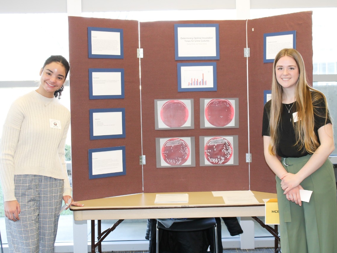 Two school-aged students smiling for the camera next to their SEFNK project.
