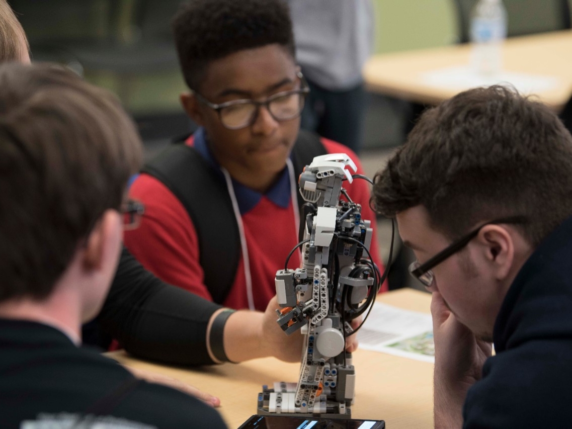 High school students programming a robot at High School STEM+H Day event