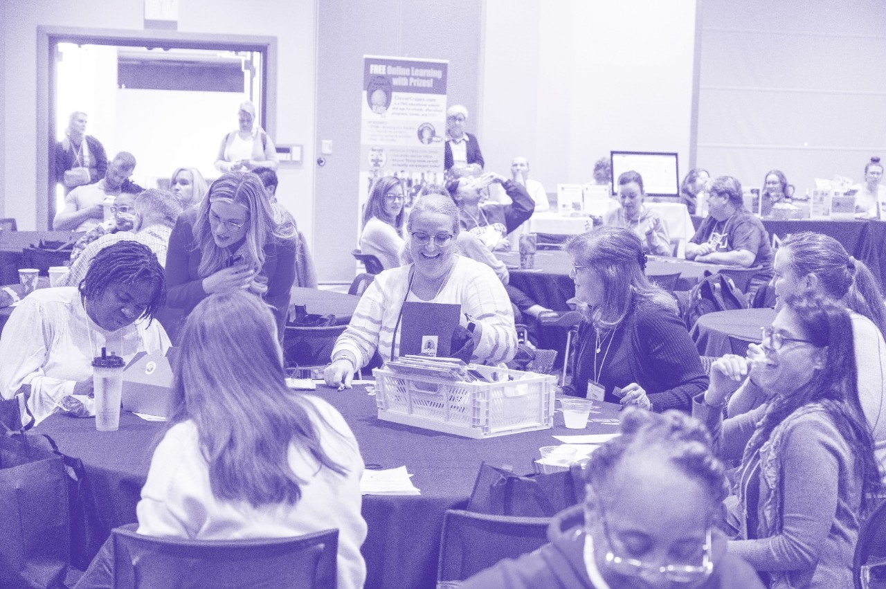 Several K-12 teachers mingle at tables during the STEM Conference.