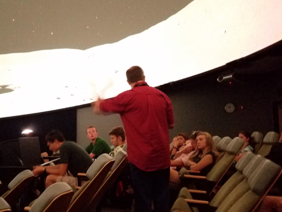Teacher giving lecture inside planetarium