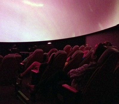 An audience watches planetarium presentation.