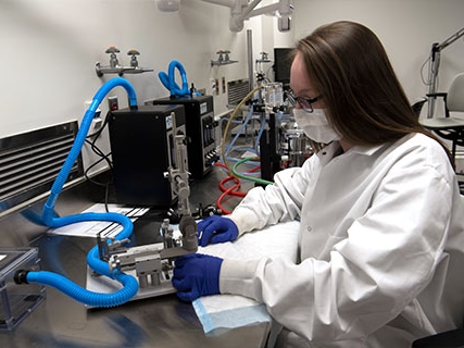 A student in protective lab gear using sophisticated laboratory equipment