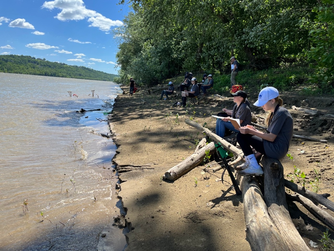Camp participants sit along the banks of the Ohio River documenting their observations in a CINSAM summer camp hosted by NKY REFS.