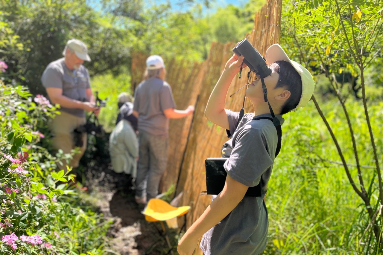 REFS visitors look for birds with binoculars through bird blinds.