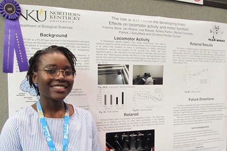 Student standing next to research presentation