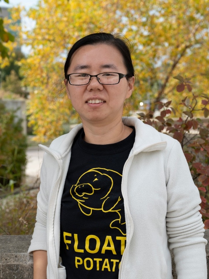 Photo of Dr. Xie outside against a backdrop of vibrant, autumn foliage.
