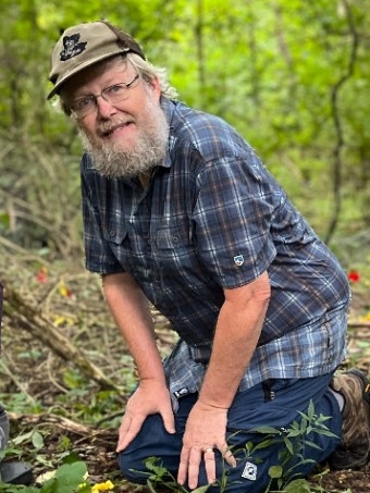 Photo of Dr. Boyce kneeling in the woods doing research.