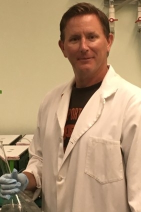 Photo of Dr. Thompson, in a lab setting, wearing a lab coat.
