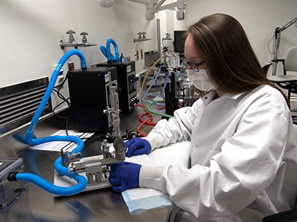 A student in protective lab gear using sophisticated laboratory equipment
