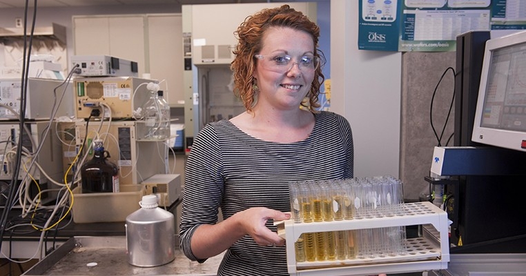 Student Chelsea Soward carrying a test tube tray in the laboratory