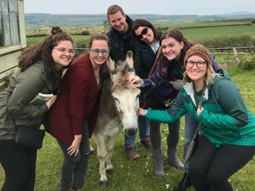 Students abroad in Ireland, posing next to a donkey.