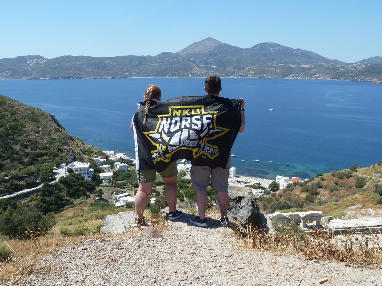 Two students with Norse banner in front of the Mediterranean Sea