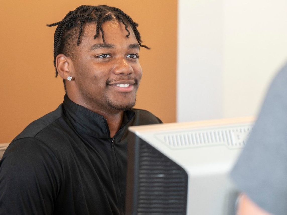 Student working at a computer, assisting a customer