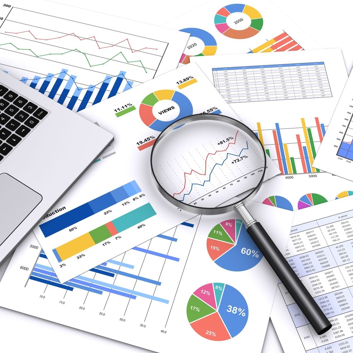 Stock photo of scattered charts and graphs with a magnifying glass on them.