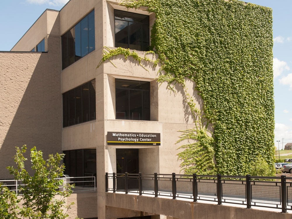 The exterior of NKU's Mathematics, Education, Psychology Center, covered in beautiful vines on a sunny day