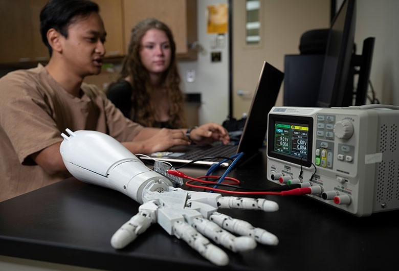 Student's in an engineering lab using robotic arms.
