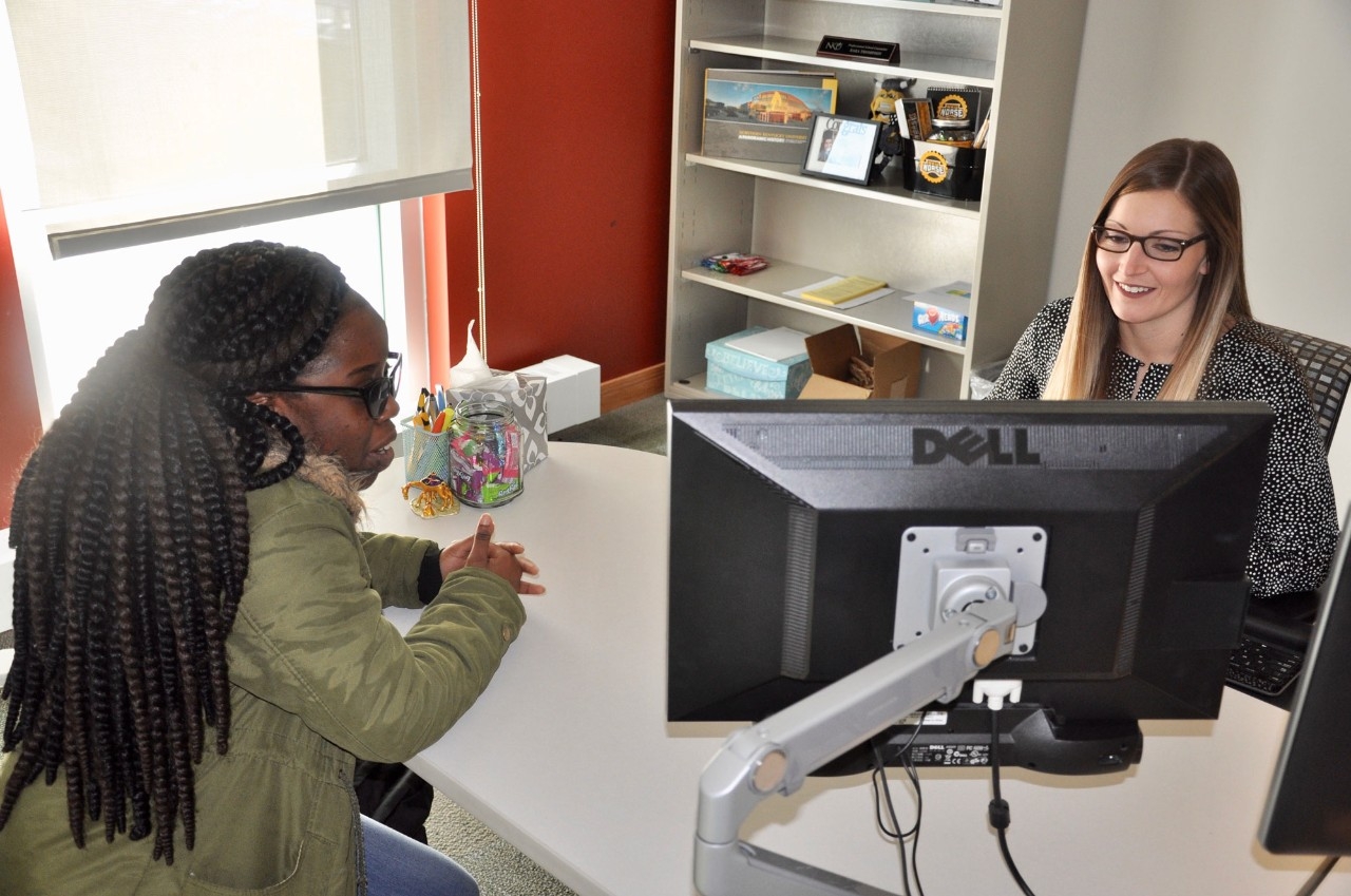 A student meets with her academic advisor in an office.