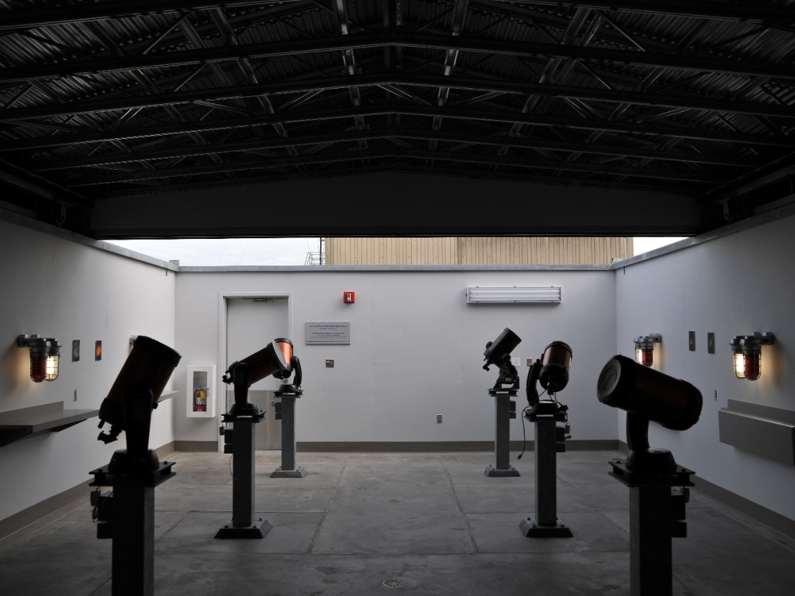 The Schneider Observiatory dimly lit by natural light with several large telescopes aiming upward