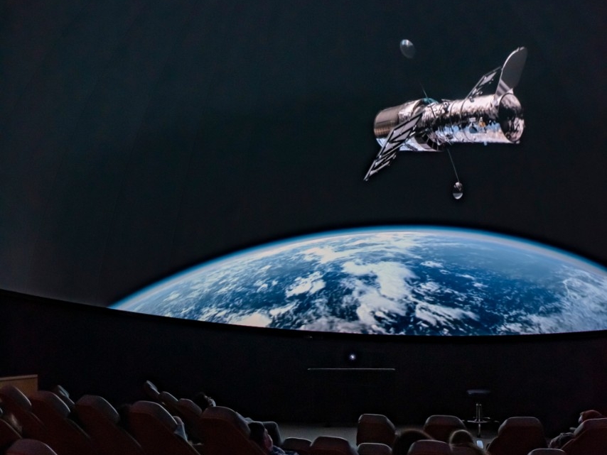 Picture of an in-progress show in the planetarium, featuring a large view of planet Earth.