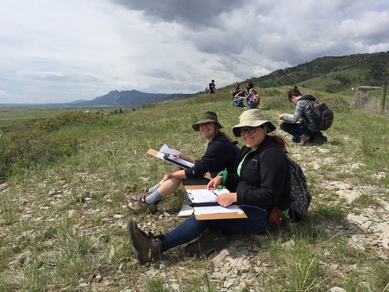 Students sitting on a hillside taking notes