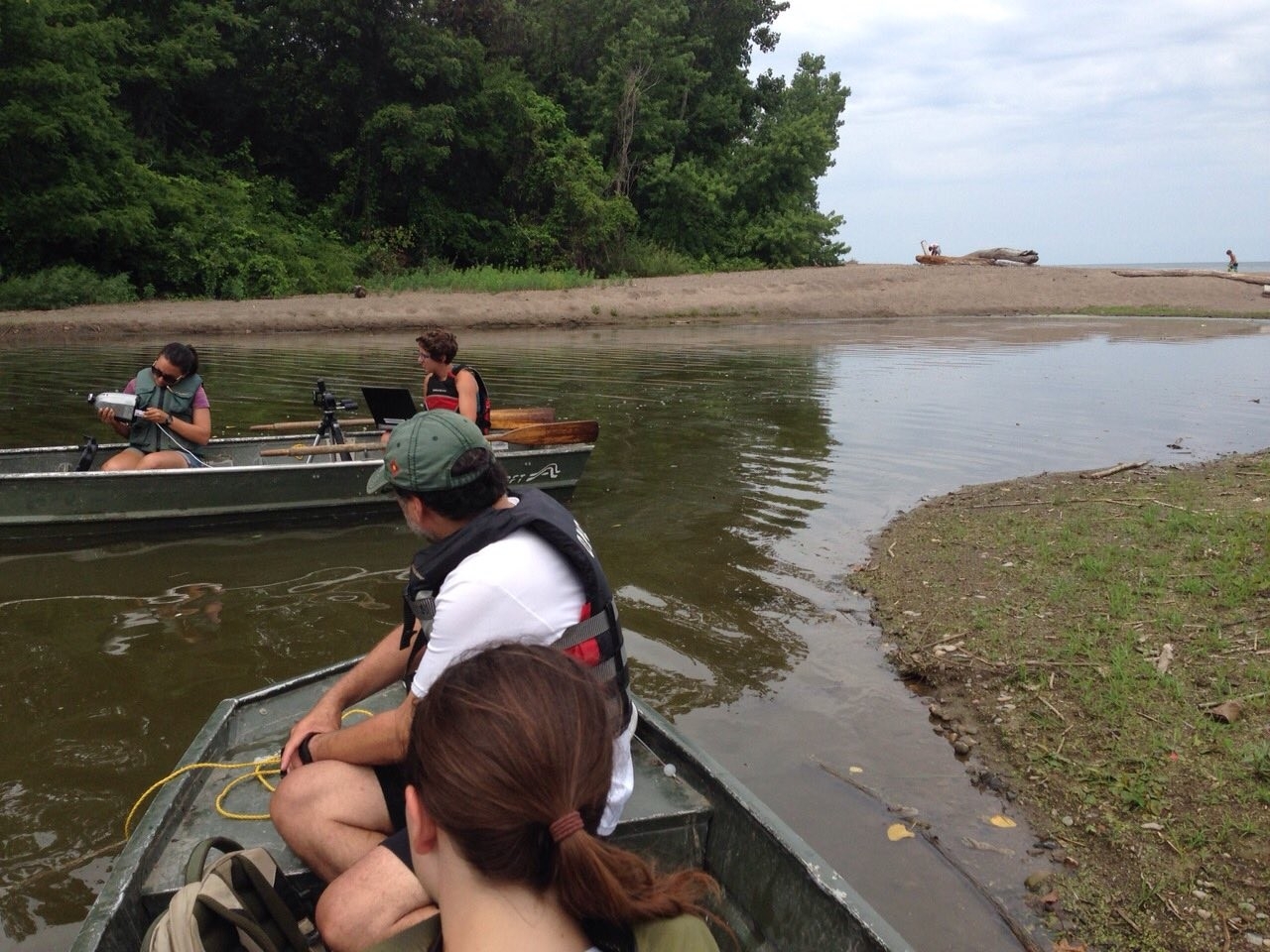 4 students gather data from canoes near the edge of a stream