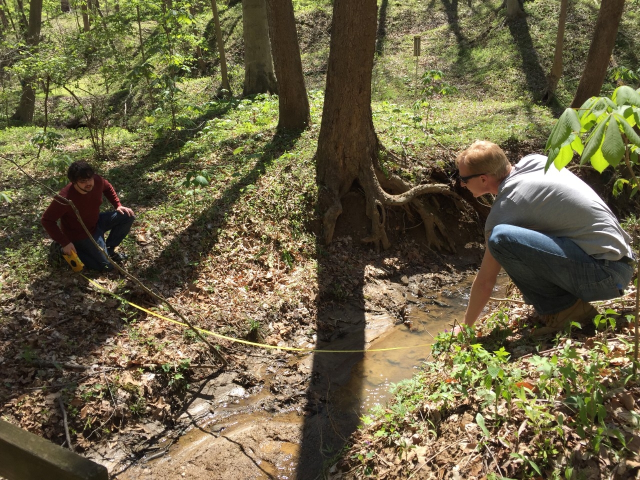 Two students measuring the width of a stream