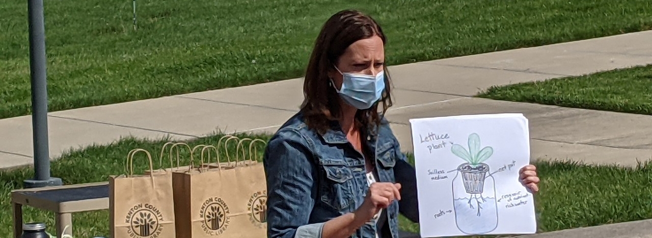 Dr. Kim Yates holding a hydroponics poster.