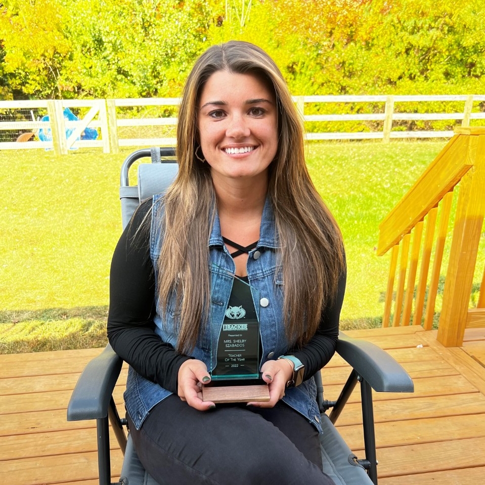 Image of Shelby Szabados sitting on her porch holding the West Clermont High School Teacher of the Year award.