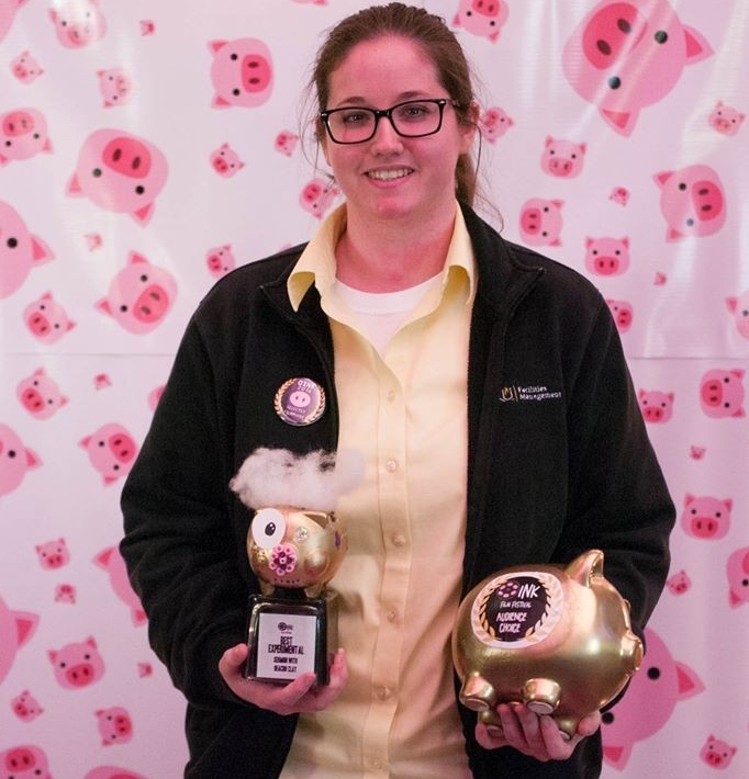 Image of an OINK film festival winning participant holding two pig shaped trophies.