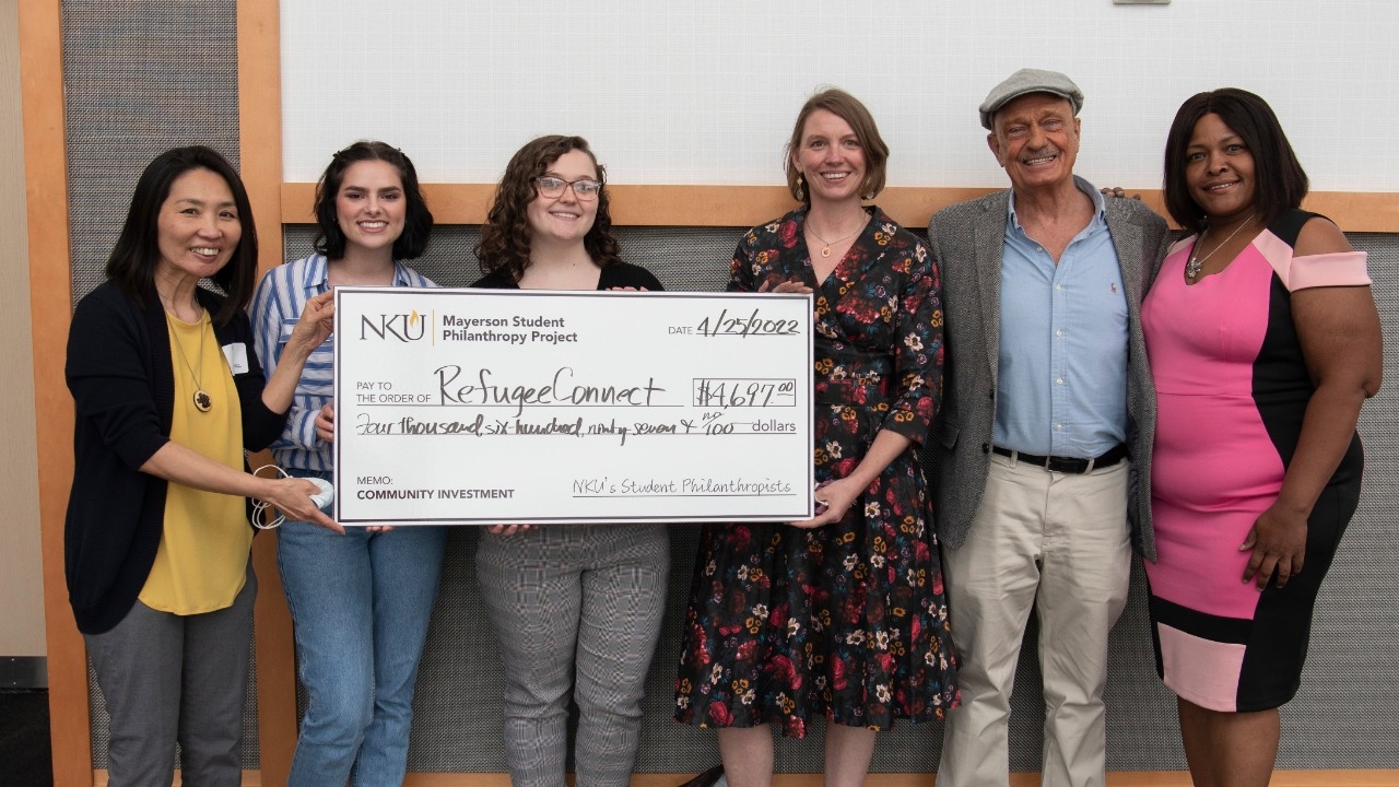 Students hold a large check to donate to a nonprofit organization