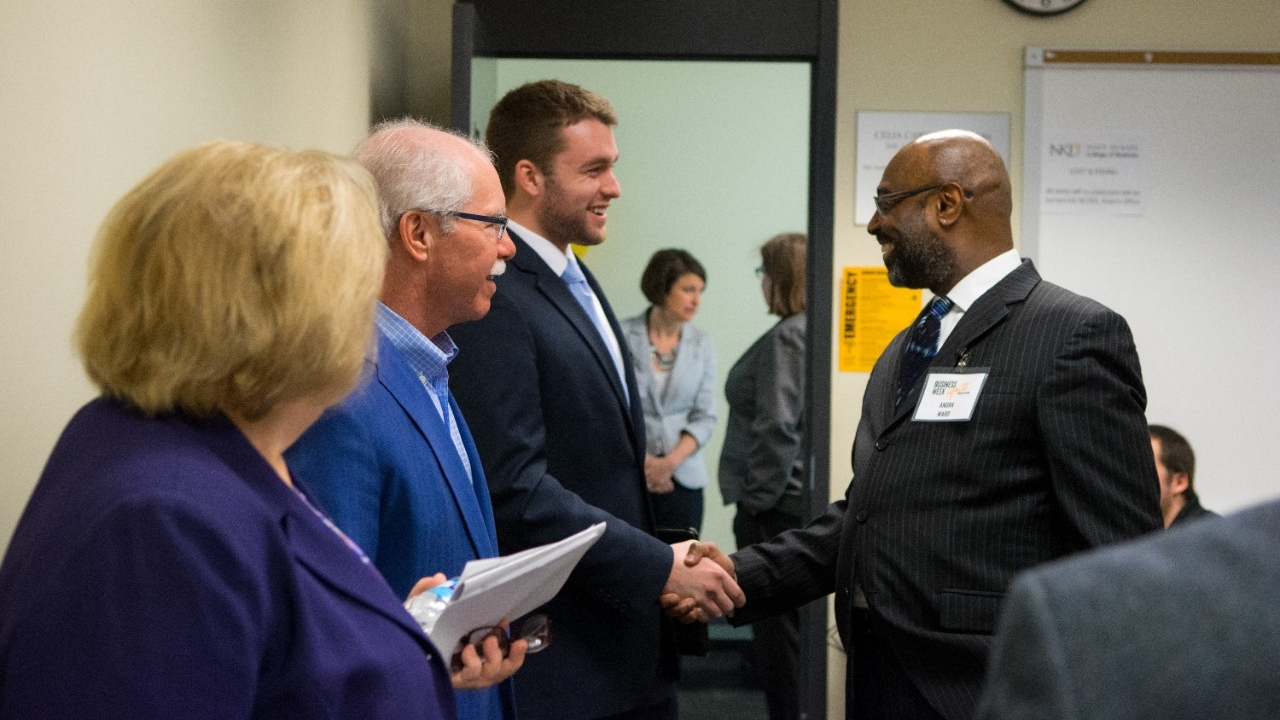 A visitor from Business Week shakes hands with an attendee