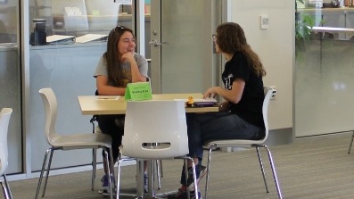 Two people have a conversation while sitting at a table