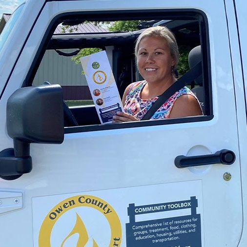 Shanna Osborne in jeep with brochure on Owen County Recovery Services resources.