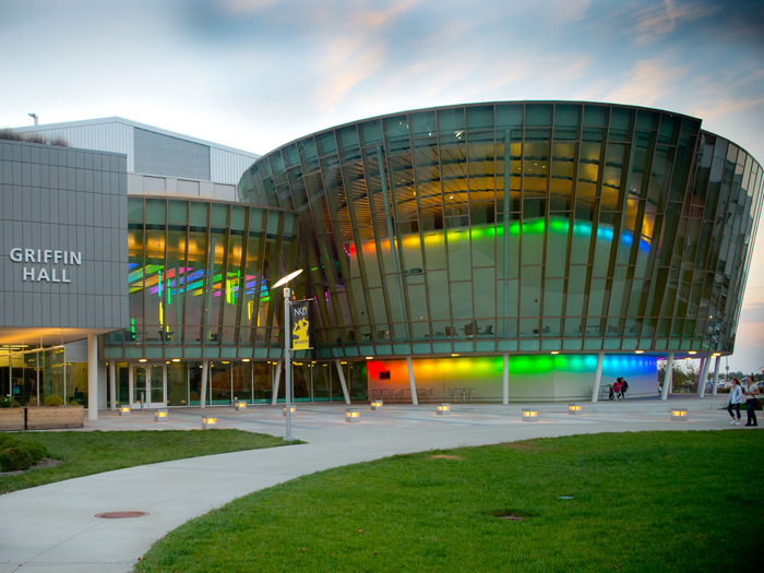 Student walking in front of lighted Griffin Hall