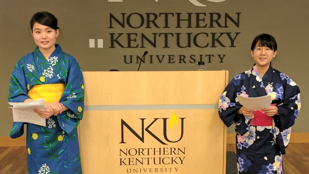Event image from NKU Global Showcase with students standing in front of NKU logo